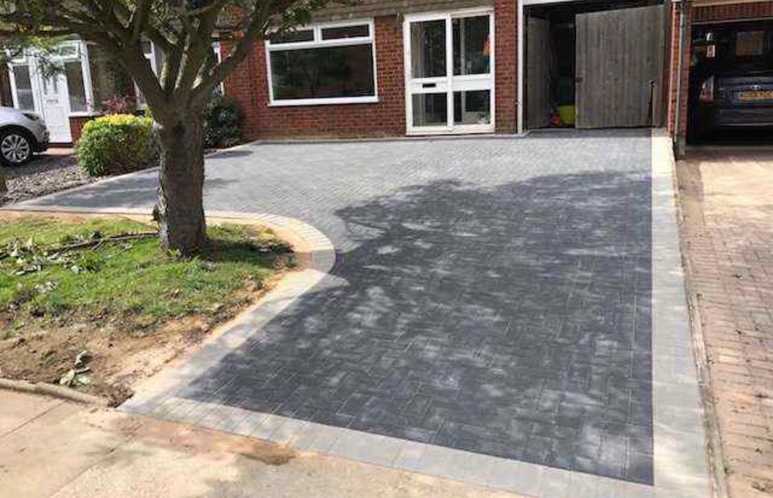 Charcoal block paved driveway with contrasting border around a mature tree