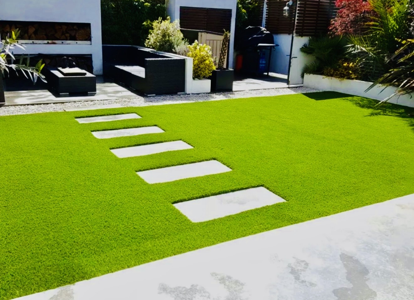 Artificial lawn with porcelain stepping stones and rendered garden walls