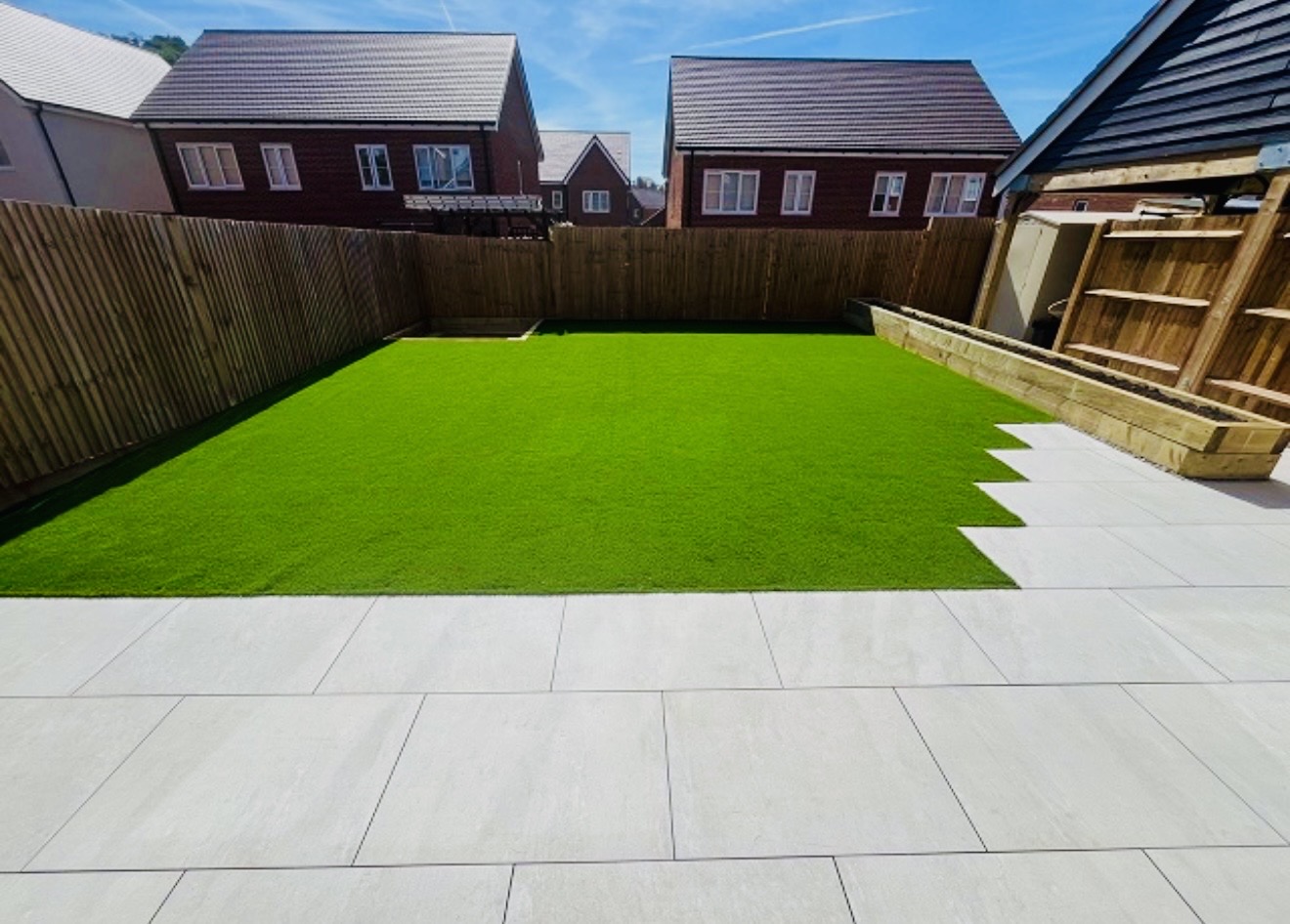 Artificial lawn with light porcelain patio and sleeper raised beds